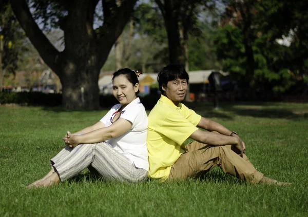 A szép pár ül a parkban a földön portréja — Stock Fotó