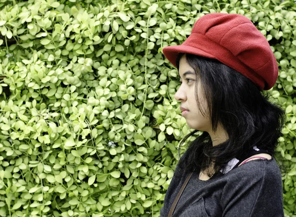 Menina asiática com chapéu vermelho em um fundo de natureza verde — Fotografia de Stock