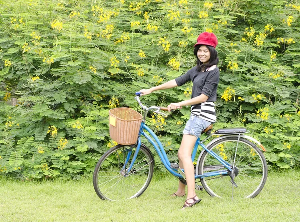 Chica sonriente montando una bicicleta en el parque —  Fotos de Stock