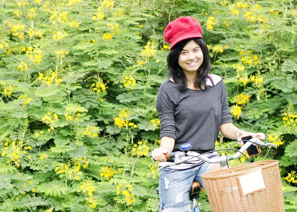 Retrato de una feliz chica sonriente montando una bicicleta en el parque . — Foto de Stock