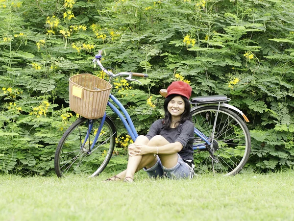 Flicka med en cykel vilar på en gräs — Stockfoto
