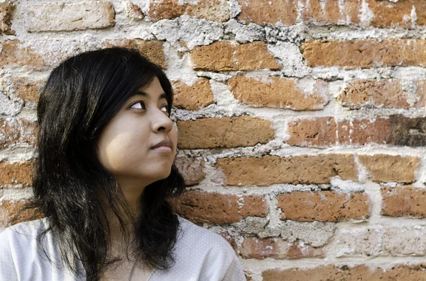 Petty young brunette woman against a Brick Wall — Stock Photo, Image