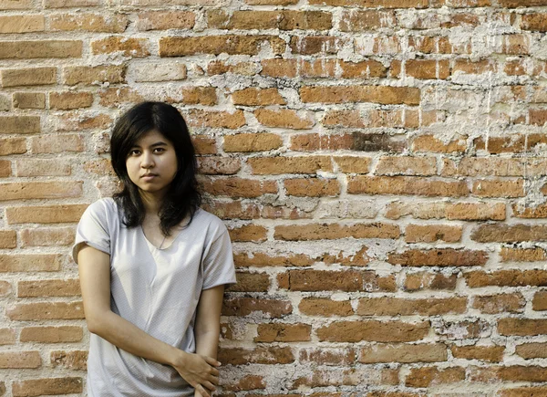 Jonge Aziatische vrouw tegen een bakstenen muur — Stockfoto