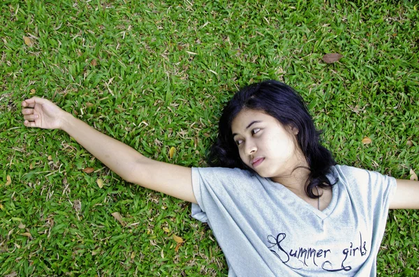 Junge asiatische Frau liegt im Gras — Stockfoto