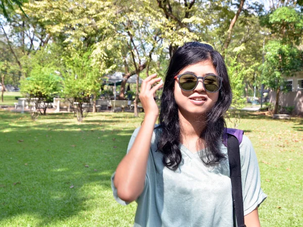 Jovem mulher olhando para a câmera através de óculos de sol — Fotografia de Stock