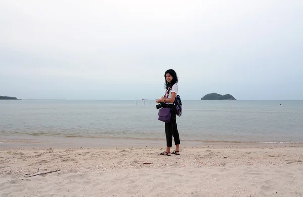 Glad ung kvinna med kamera på stranden — Stockfoto