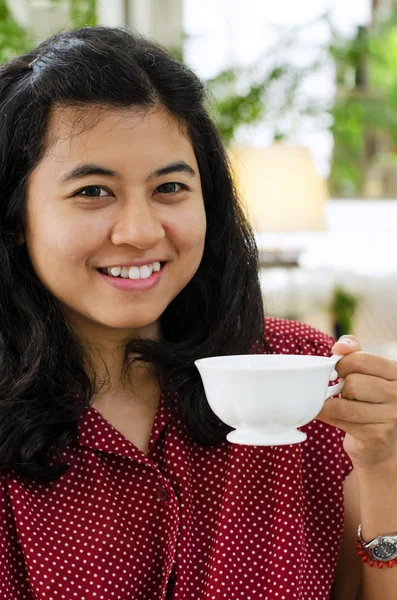 Junge Frau nippt an Tee aus einer Tasse — Stockfoto