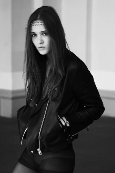 Young naughty lady standing in a leather jacket and tights — Stock Photo, Image