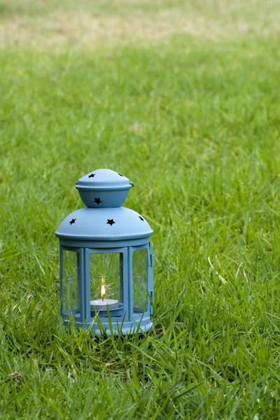 Blaue Laterne, mit brennender Kerze drinnen, auf grünem Gras — Stockfoto