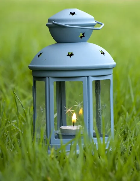 Linterna azul, con vela encendida en el interior, sobre hierba verde —  Fotos de Stock
