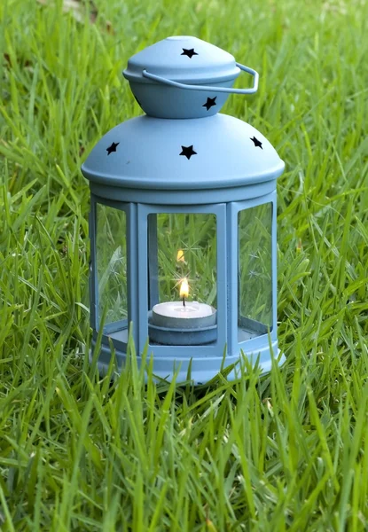 Blaue Laterne, mit brennender Kerze drinnen, auf grünem Gras — Stockfoto