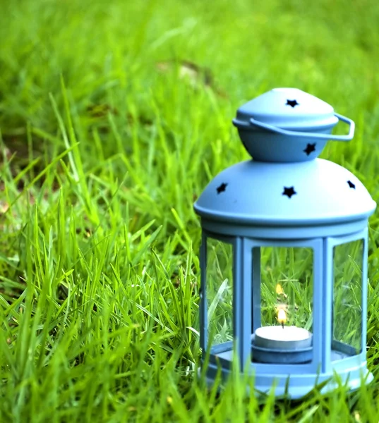 Blue Lantern, with burning candle inside, on green grass — Stock Photo, Image