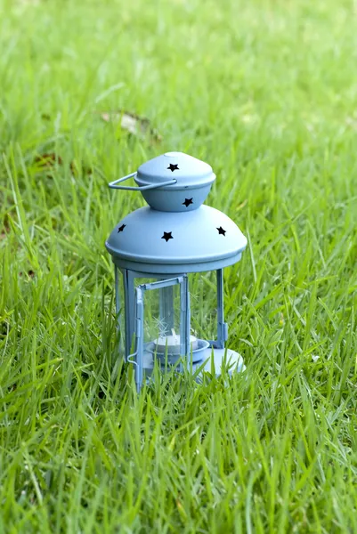 Linterna azul, con vela encendida en el interior, sobre hierba verde — Foto de Stock