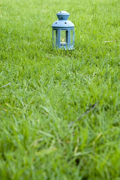 Modrá Lucerna, s hořící svíčkou uvnitř, na zelené trávě — Stock fotografie