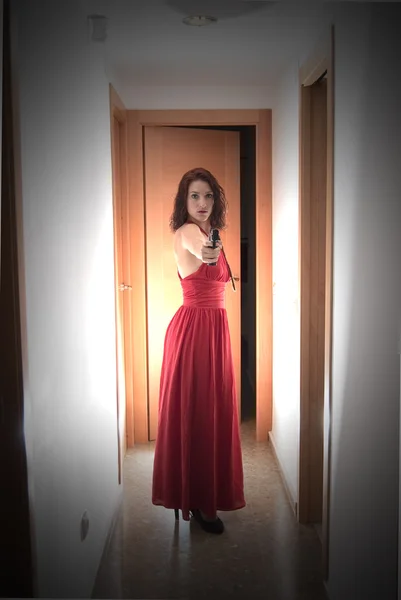 Hermosa mujer con un vestido rojo y un arma — Foto de Stock