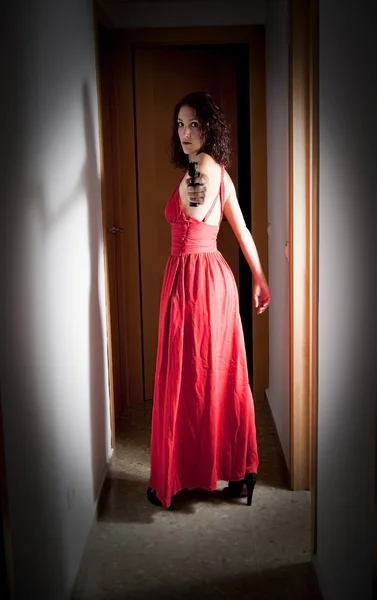 Schöne Frau mit rotem Kleid und Pistole — Stockfoto