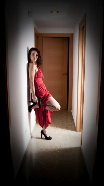 Krásná žena s červených šatech a zbraň — Stock fotografie