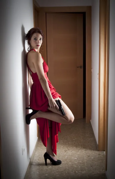 Schöne Frau mit rotem Kleid und Pistole — Stockfoto