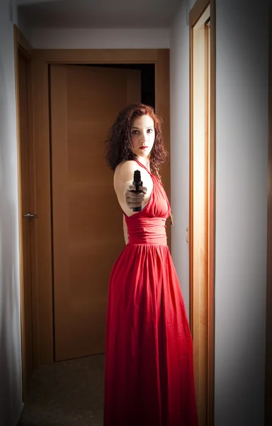 Beautiful  Woman with a red dress and a gun — Stock Photo, Image