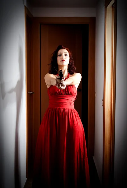 Belle femme avec une robe rouge et un pistolet — Photo