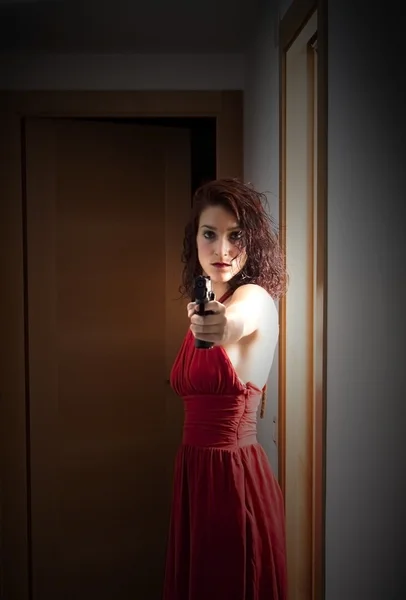 Beautiful  Woman with a red dress and a gun — Stock Photo, Image