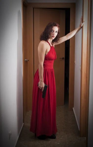 Vacker kvinna med en röd klänning och en pistol — Stockfoto
