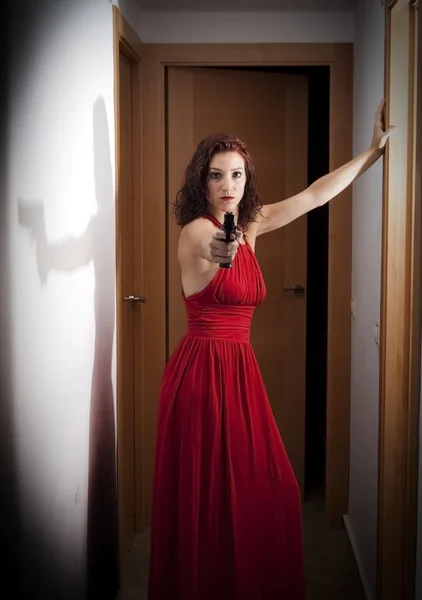 Beautiful  Woman with a red dress and a gun — Stock Photo, Image