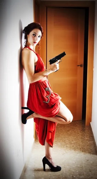 Beautiful  Woman with a red dress and a gun — Stock Photo, Image