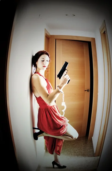 Mooie vrouw met een rode jurk en een pistool — Stockfoto