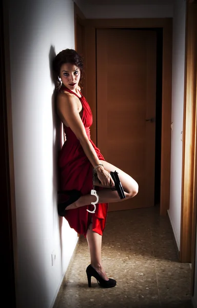 Όμορφη γυναίκα με ένα κόκκινο φόρεμα και ένα πυροβόλο όπλο — Φωτογραφία Αρχείου