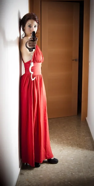 Beautiful  Woman with a red dress and a gun — Stock Photo, Image