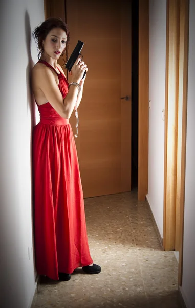 Hermosa mujer con un vestido rojo y un arma — Foto de Stock