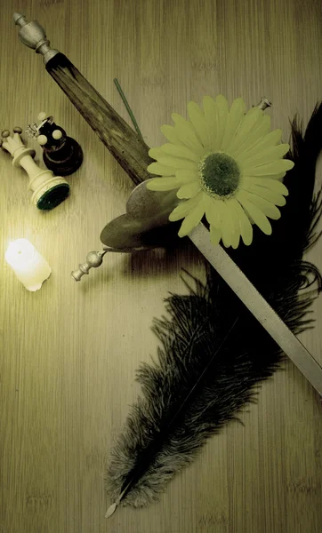 Ancient sword, a candle, a yellow flower, two pieces of chess an — Stock Photo, Image