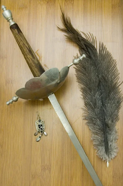 Ancient sword, earring of women and old writing pen on a wooden — Stock Photo, Image