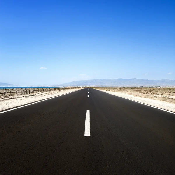Straight road in desert seascape. Cabo de Gata, Andalusia. — Stock Photo, Image