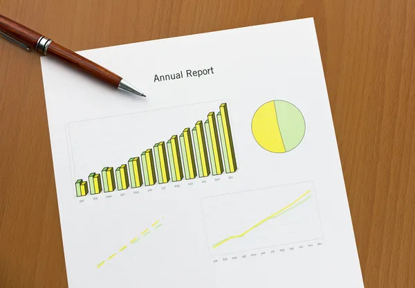 Carta da stampa annuale, penna su scrivania. Statistiche mensili . — Foto Stock