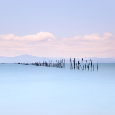 Fishing poles and soft water on sea landscape. Long exposure. clipart