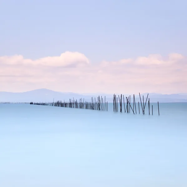 Fishing poles and soft water on sea landscape. Long exposure. — Stock Photo, Image