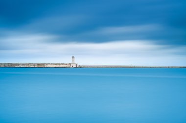 Livorno port lighthouse, breakwater and soft water under cloudy sky clipart