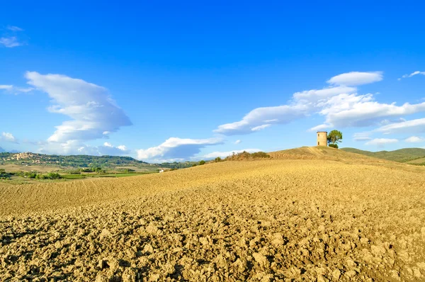 Toscana, Maremma paisaje. Torre rural, campo arado, pueblo de fondo . — Foto de Stock