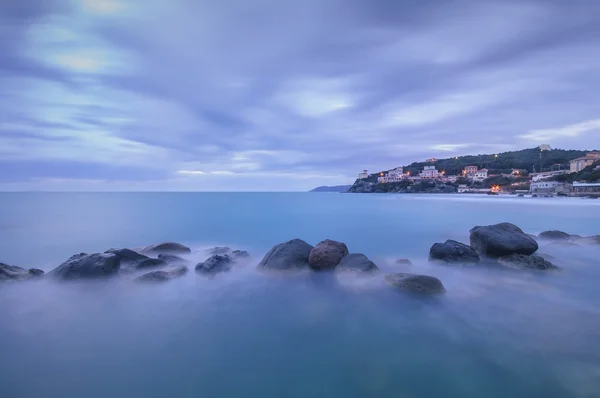 Sötét sziklák a kék óceán, a twilight. Castiglioncello, Olaszország — Stock Fotó