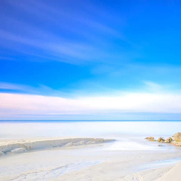 White sand dunes beach, rocks, ocean and sky