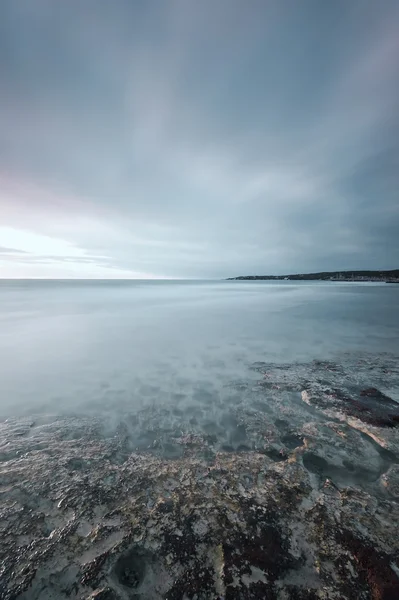 Rocas sumergidas, océano y cielo nublado en la playa de la bahía —  Fotos de Stock
