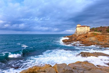 okyanus dalgası ve boccale Kalesi landmark cliff kayanın üzerine. Toskana, İtalya.