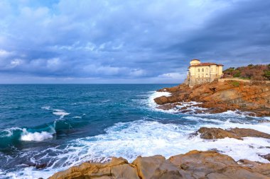 Ocean wave and boccale castle landmark on cliff rock. Tuscany, Italy. clipart
