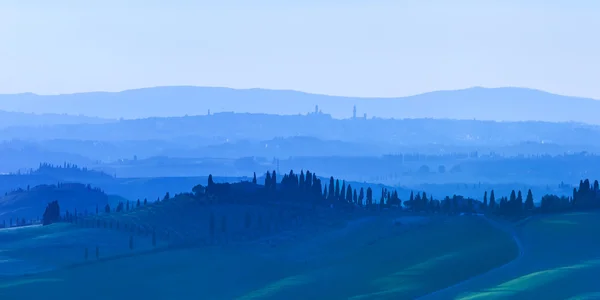 Siena, sanfte Hügel bei blauem Sonnenuntergang. ländliche Landschaft mit Zypressen. Toskana, Italien — Stockfoto