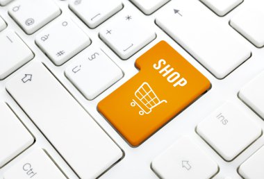 Shop business concept. Orange shopping cart button or key on white keyboard clipart