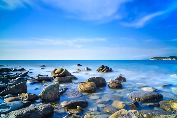 Baratti hnědák, skály v modrém oceánu na západ slunce. Toskánsko, Itálie. — Stock fotografie