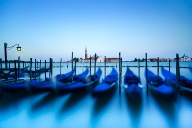 Venice, gondolas or gondole on sunset and church on background. Italy