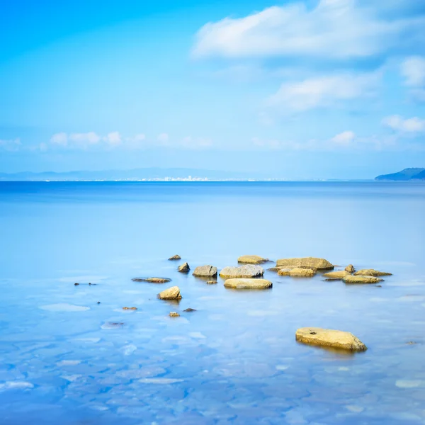 Vallende stenen in een blauwe oceaan in een zee baai. Punta ala, Toscane, Italië — Stockfoto